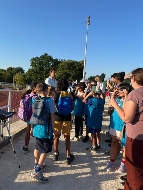 Groupe d'enfants observant l'éclipse avec des lunettes de protection au stade Montbauron